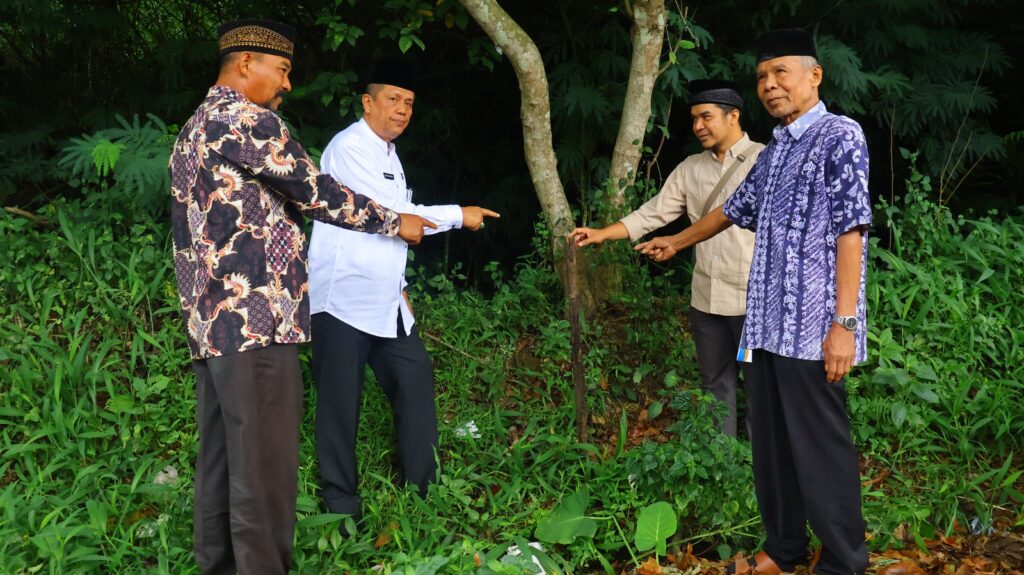 Wakil Wali Kota dan Tokoh Adat, berdiri di area berumput dan menunjuk ke satu titik di tanah dekat pohon, sebagai simbol dimulainya pembangunan gerbang selamat datang di kawasan Ngalau, Payakumbuh.