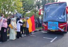 Sejumlah pejabat dan warga melepas keberangkatan rombongan jemaah haji Kota Payakumbuh menggunakan bus pariwisata berwarna merah, sambil melambaikan tangan dan mengibarkan bendera.