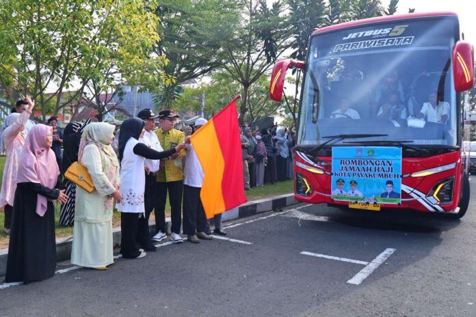 Sejumlah pejabat dan warga melepas keberangkatan rombongan jemaah haji Kota Payakumbuh menggunakan bus pariwisata berwarna merah, sambil melambaikan tangan dan mengibarkan bendera.