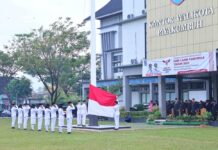 Pasukan pengibar bendera sedang melaksanakan upacara peringatan Hari Lahir Pancasila 2025 di halaman Kantor Wali Kota Payakumbuh, dengan para peserta upacara memberikan hormat saat bendera Merah Putih dikibarkan.