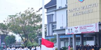 Pasukan pengibar bendera sedang melaksanakan upacara peringatan Hari Lahir Pancasila 2025 di halaman Kantor Wali Kota Payakumbuh, dengan para peserta upacara memberikan hormat saat bendera Merah Putih dikibarkan.