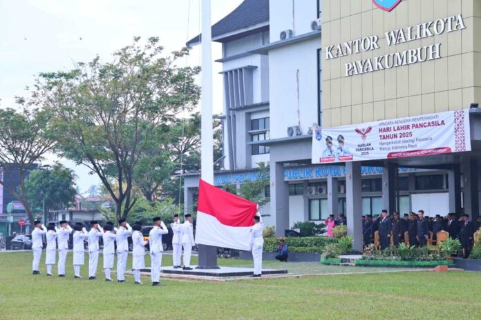 Pasukan pengibar bendera sedang melaksanakan upacara peringatan Hari Lahir Pancasila 2025 di halaman Kantor Wali Kota Payakumbuh, dengan para peserta upacara memberikan hormat saat bendera Merah Putih dikibarkan.