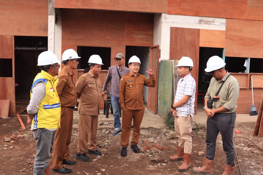 Wali Kota Payakumbuh Zulmaeta bersama tim dinas meninjau proyek pembangunan dengan mengenakan helm pengaman di lokasi konstruksi.
