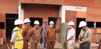 Wali Kota Payakumbuh Zulmaeta bersama tim dinas meninjau proyek pembangunan dengan mengenakan helm pengaman di lokasi konstruksi.