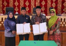 Sekda Payakumbuh Rida Ananda dan Ketua DPRD Wirman Putra menunjukkan dokumen nota kesepakatan perubahan KUA-PPAS APBD 2025, didampingi dua pejabat perempuan dalam rapat paripurna di DPRD Kota Payakumbuh.