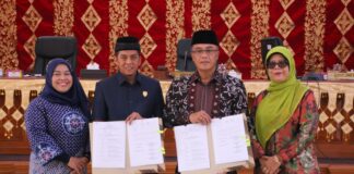 Sekda Payakumbuh Rida Ananda dan Ketua DPRD Wirman Putra menunjukkan dokumen nota kesepakatan perubahan KUA-PPAS APBD 2025, didampingi dua pejabat perempuan dalam rapat paripurna di DPRD Kota Payakumbuh.