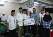 Sekda Payakumbuh Rida Ananda menyerahkan simbolis bantuan Beasiswa Mentari dari Lazismu kepada siswa SLTA, disaksikan pengurus dan penerima beasiswa.