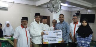 Sekda Payakumbuh Rida Ananda menyerahkan simbolis bantuan Beasiswa Mentari dari Lazismu kepada siswa SLTA, disaksikan pengurus dan penerima beasiswa.
