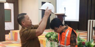 Simbolis penyematan helm keselamatan oleh perwakilan Pemko Payakumbuh dalam kegiatan uji sertifikasi tenaga kerja konstruksi