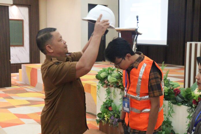 Simbolis penyematan helm keselamatan oleh perwakilan Pemko Payakumbuh dalam kegiatan uji sertifikasi tenaga kerja konstruksi