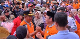 Wali Kota dan Wakil Wali Kota Payakumbuh berjabat tangan dengan penuh semangat di tengah kerumunan warga saat Pawai Alegoris HUT RI ke-80.