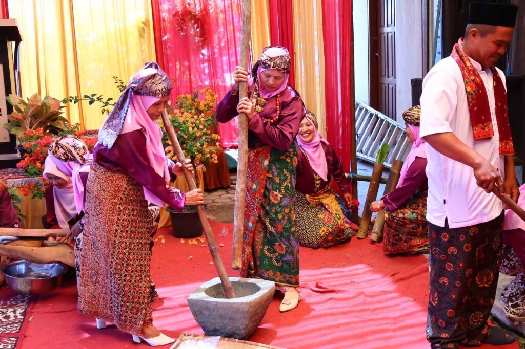 Perempuan Minangkabau mengenakan pakaian adat melakukan prosesi menumbuk padi dalam acara Satu Nagori Satu Iven di Payakumbuh.