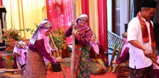 Perempuan Minangkabau mengenakan pakaian adat melakukan prosesi menumbuk padi dalam acara Satu Nagori Satu Iven di Payakumbuh.