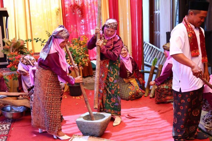 Perempuan Minangkabau mengenakan pakaian adat melakukan prosesi menumbuk padi dalam acara Satu Nagori Satu Iven di Payakumbuh.