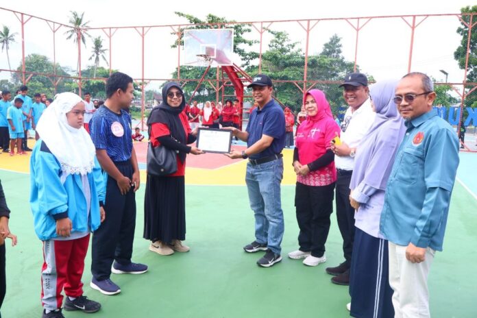 Asisten I menyerahkan piagam penghargaan kepada perwakilan dalam rangkaian peringatan Haornas 2025 di Payakumbuh, disaksikan peserta dan tamu undangan.