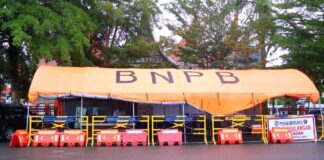 Tenda posko BNPB berwarna oranye dengan pagar pengaman dan spanduk bertuliskan "Posko Bersama Penanggulangan Bencana" di Kota Payakumbuh.