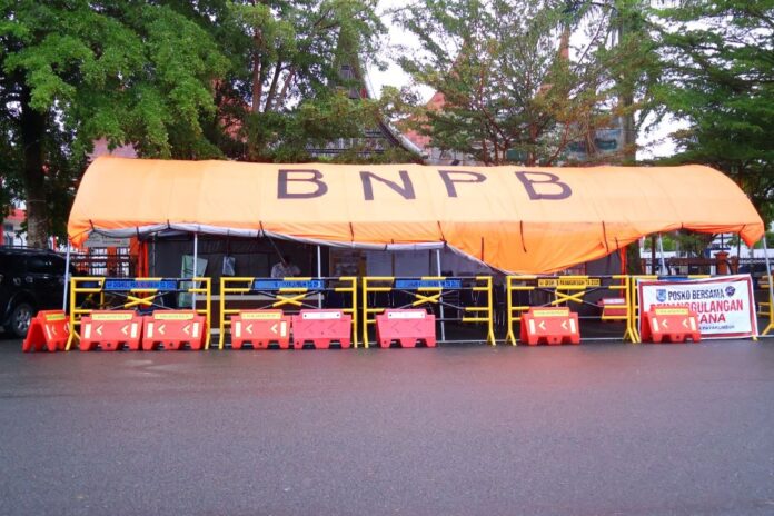 Posko Sementara Penanggulangan Bencana Pasar Payakumbuh Beroperasi di Depan Kantor Pos Tenda posko BNPB berwarna oranye dengan pagar pengaman dan spanduk bertuliskan