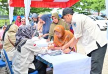 Petugas Pemko Payakumbuh melayani warga yang antre membeli kebutuhan pokok dalam Gerakan Pangan Murah di Pasar Padang Kaduduak.