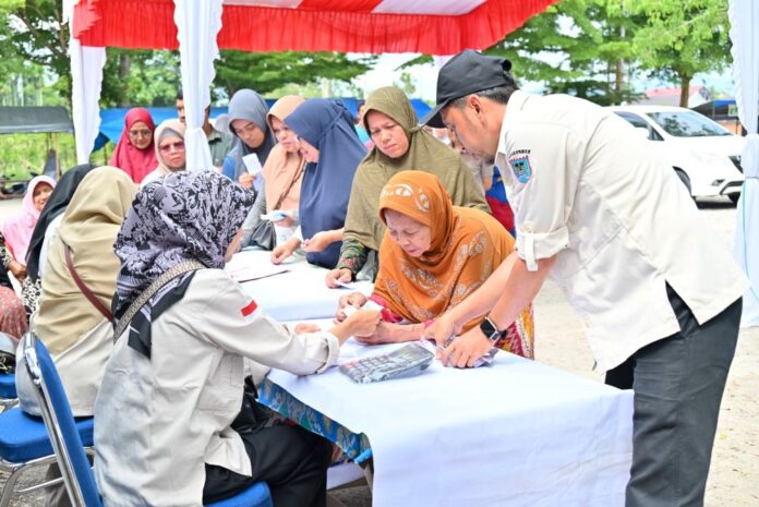 Petugas Pemko Payakumbuh melayani warga yang antre membeli kebutuhan pokok dalam Gerakan Pangan Murah di Pasar Padang Kaduduak.