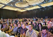 Para peserta Rakornas Kepegawaian 2025 memenuhi ruang konferensi dengan; sejumlah pejabat daerah duduk di barisan depan mengenakan batik dan tanda pengenal acara.