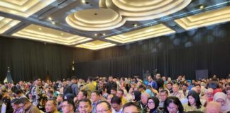 Para peserta Rakornas Kepegawaian 2025 memenuhi ruang konferensi dengan; sejumlah pejabat daerah duduk di barisan depan mengenakan batik dan tanda pengenal acara.