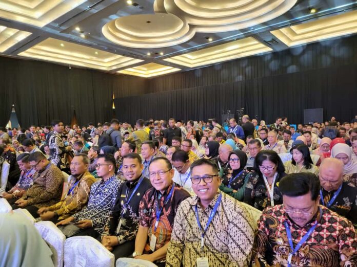 Para peserta Rakornas Kepegawaian 2025 memenuhi ruang konferensi dengan; sejumlah pejabat daerah duduk di barisan depan mengenakan batik dan tanda pengenal acara.