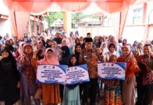 Sekelompok warga penerima Bantuan Langsung Tunai Sementara Kesejahteraan Rakyat (BLTS Kesra) 2025 di Payakumbuh berfoto bersama Wakil Wali Kota Payakumbuh saat penyaluran bantuan, sambil mengangkat tangan penuh semangat dan memegang papan informasi nominal bantuan.