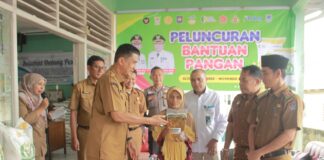 Asisten II Setda Payakumbuh Yasrizal menyerahkan bantuan pangan beras dan minyak goreng kepada seorang warga penerima manfaat pada peluncuran bantuan pangan CPP di Kelurahan Balai Jaring.