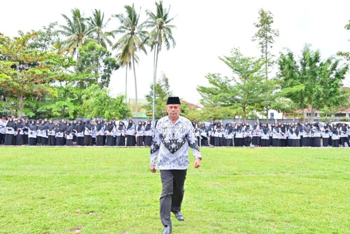 Wakil Wali Kota Payakumbuh berjalan di depan barisan ratusan guru berseragam PGRI saat upacara Hari Guru Nasional di halaman Balai Kota Payakumbuh.