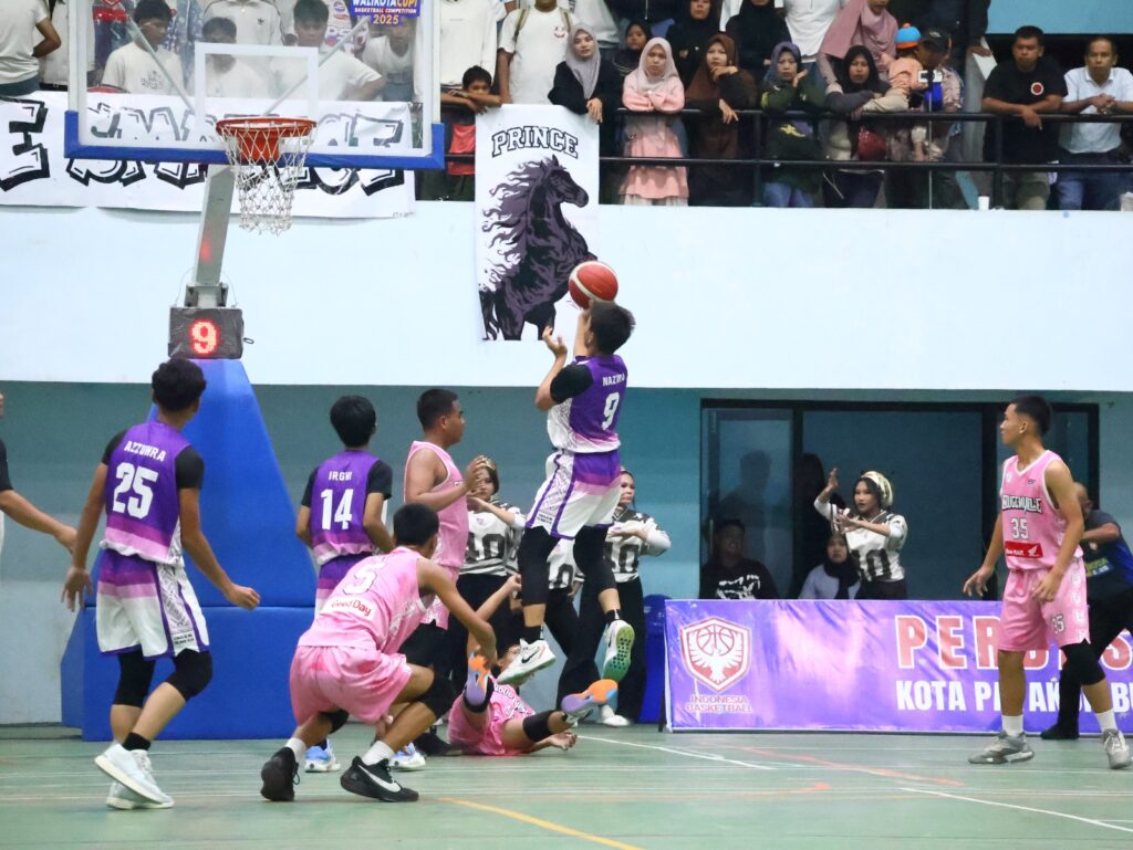 Pemain SMA ICBS dengan seragam ungu melakukan tembakan lay-up ke arah ring, dijaga pemain SMA Negeri 1 Payakumbuh yang mengenakan seragam pink, pada final putra Walikota Cup I 2025 di GOR Nan Ampek, disaksikan suporter yang memenuhi tribun.