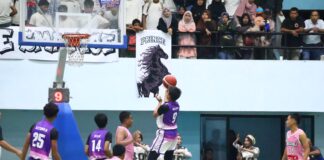Pemain SMA ICBS dengan seragam ungu melakukan tembakan lay-up ke arah ring, dijaga pemain SMA Negeri 1 Payakumbuh yang mengenakan seragam pink, pada final putra Walikota Cup I 2025 di GOR Nan Ampek, disaksikan suporter yang memenuhi tribun.