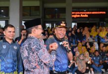 HUT KORPRI ke-54 Payakumbuh Tetap Meriah di Tengah Hujan, Kekompakan ASN Jadi Sorotan Wali Kota Payakumbuh Zulmaeta berjabat tangan dengan Wakil Wali Kota Payakumbuh Elzadaswarman sambil berbicara menggunakan mikrofon pada peringatan HUT ke-54 KORPRI, di hadapan ASN yang memadati area acara.