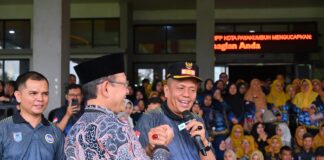 Wali Kota Payakumbuh Zulmaeta berjabat tangan dengan Wakil Wali Kota Payakumbuh Elzadaswarman sambil berbicara menggunakan mikrofon pada peringatan HUT ke-54 KORPRI, di hadapan ASN yang memadati area acara.