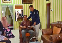 Sekda Kota Payakumbuh, Rida Ananda, berdiri memberikan dukungan dan bantuan kepada seorang anggota Korpri yang sedang sakit di ruang tamu rumahnya.