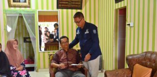 Sekda Kota Payakumbuh, Rida Ananda, berdiri memberikan dukungan dan bantuan kepada seorang anggota Korpri yang sedang sakit di ruang tamu rumahnya.