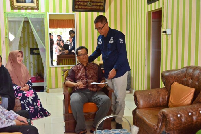 Sekda Kota Payakumbuh, Rida Ananda, berdiri memberikan dukungan dan bantuan kepada seorang anggota Korpri yang sedang sakit di ruang tamu rumahnya.