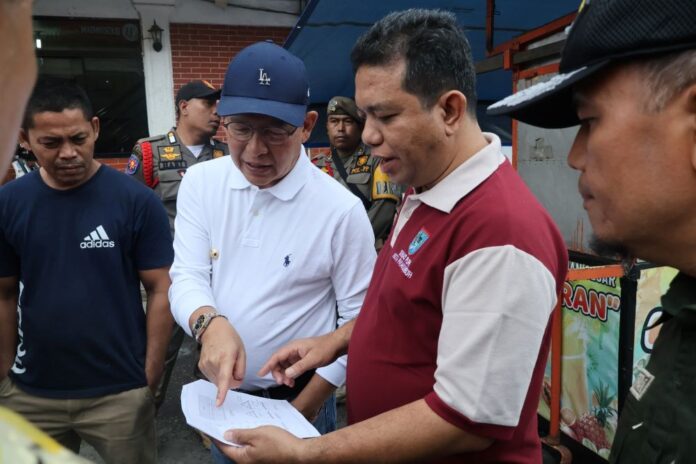 Wali Kota Payakumbuh, Zulmaeta meninjau dokumen pembangunan Pasar Payakumbuh bersama Kadis PUPR, Muslim di area pasar, disaksikan petugas Satpol PP.