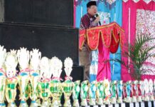 Wali Kota Payakumbuh menyampaikan sambutan pada Anugerah Prestasi Pendidikan 2025 dengan deretan piala penghargaan di depan panggung.