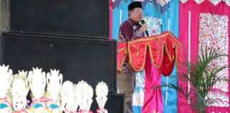 Wali Kota Payakumbuh menyampaikan sambutan pada Anugerah Prestasi Pendidikan 2025 dengan deretan piala penghargaan di depan panggung.