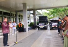 wakil walikota melepas keberangkatan bantuan kemanusiaan dengan dua truk logistik yang terparkir di halaman kantor.