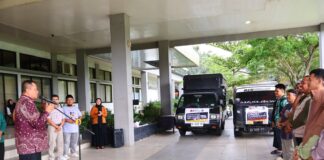 wakil walikota melepas keberangkatan bantuan kemanusiaan dengan dua truk logistik yang terparkir di halaman kantor.