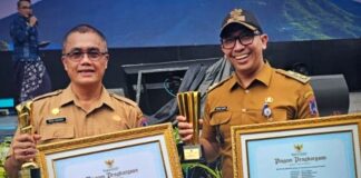 Sekretaris Daerah Kota Payakumbuh Rida Ananda dan Lurah Koto Tangah Khalid Zamri memegang piagam penghargaan dan trofi pada ajang Pemdeskel Award Nasional 2025.